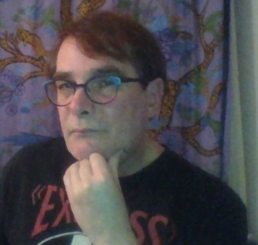 Tony Fonseca facing the viewer with his hand under his chin, looking thoughtful.